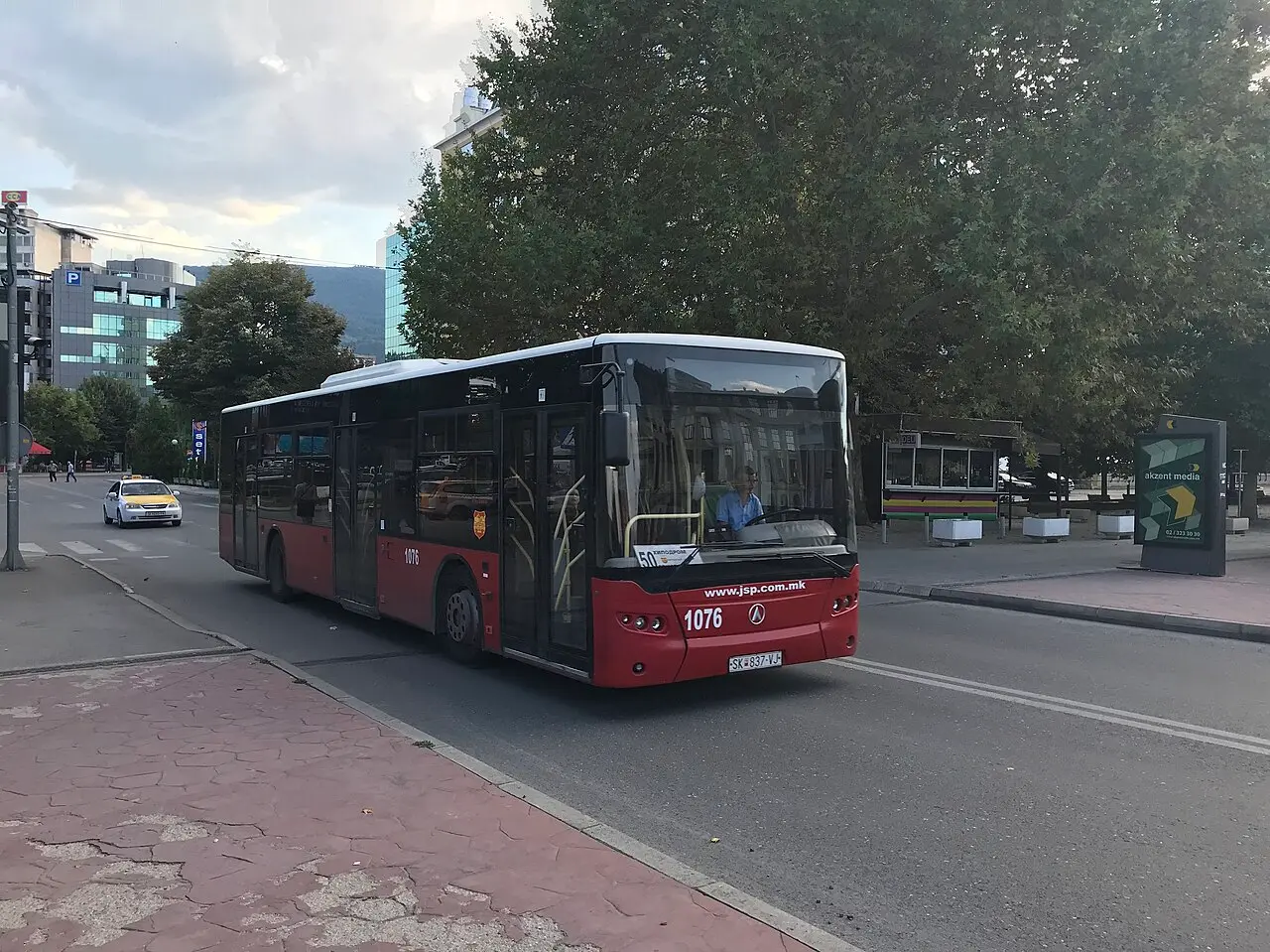A red Skopje city bus waiting at a stop in the city centre