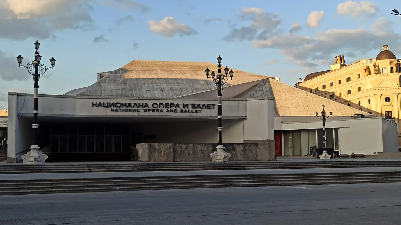 The concrete facade of the National Opera and Ballet in Skopje at golden hour, with its own name lettered above the entrance in Macedonian and English