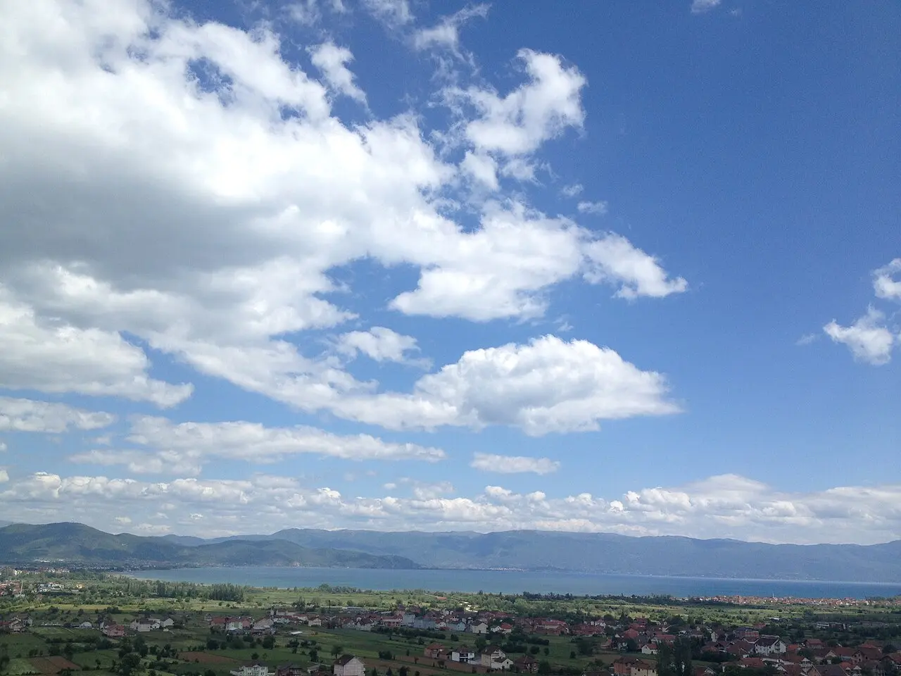 Wide view of Lake Ohrid with fields on the shore and mountains beyond