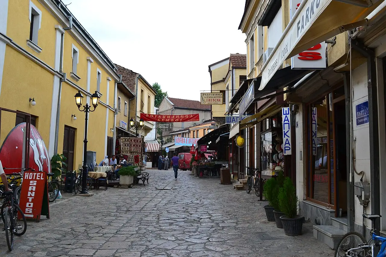 A cobbled street in Skopje's Old Bazaar lined with shops, awnings and a hotel sign