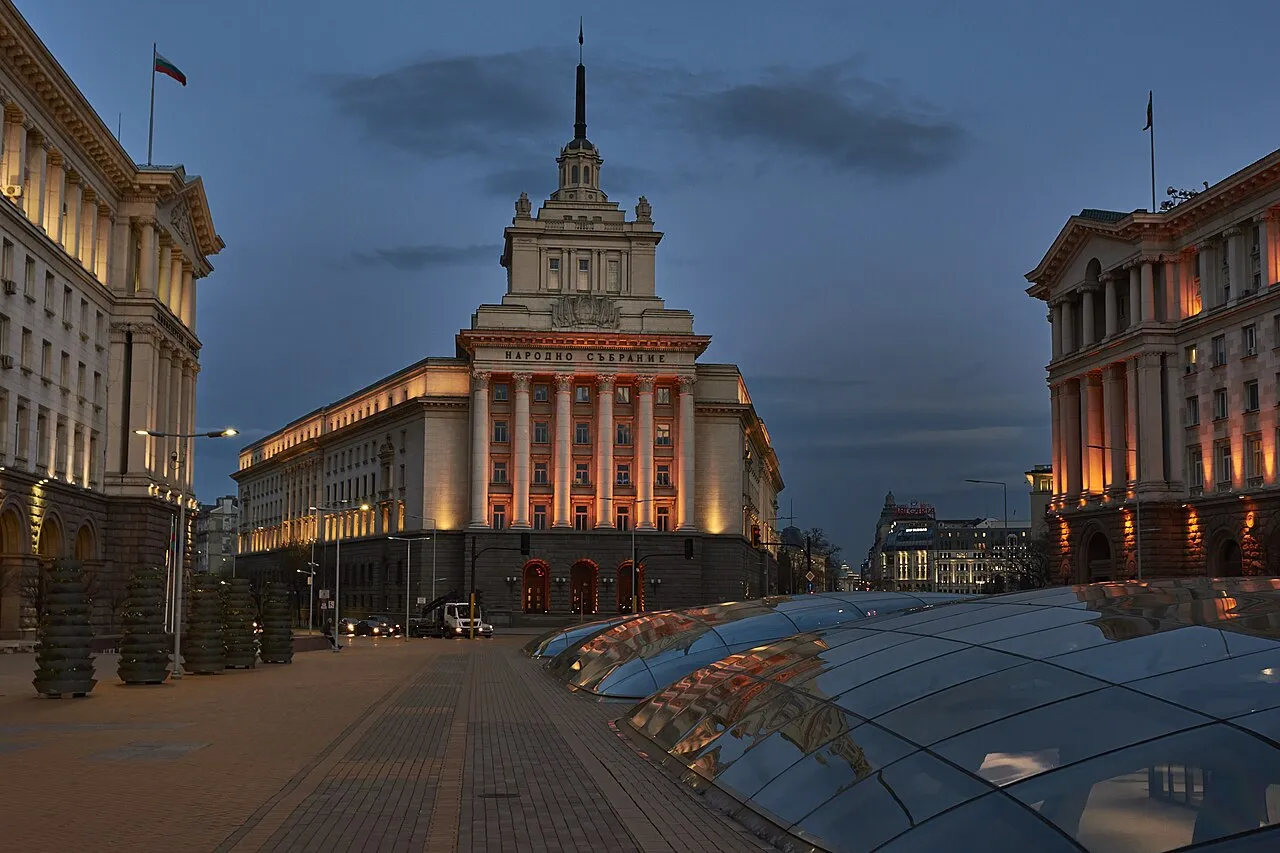 The former Communist Party headquarters in Sofia lit at dusk, with glass domes over the Serdica ruins in the foreground