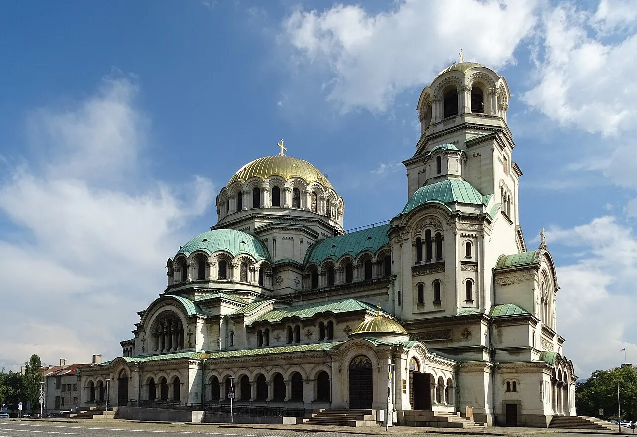 The gold and green domes of Alexander Nevsky Cathedral in Sofia under a clear blue sky