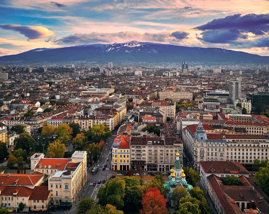 Sofia's rooftops at sunset with the snow-capped peak of Vitosha mountain rising behind the city