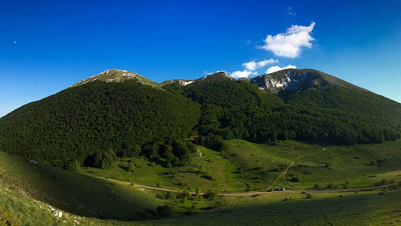 High country on Galicica: a meadow, a dirt track, a red roof and snow peaks - no lakes in the frame