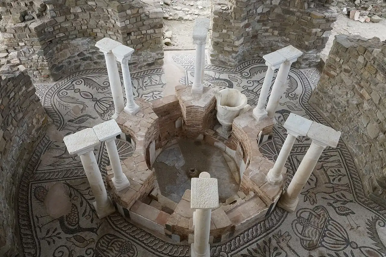 The circular baptismal font of the Episcopal Basilica at Stobi surrounded by white columns and mosaic flooring