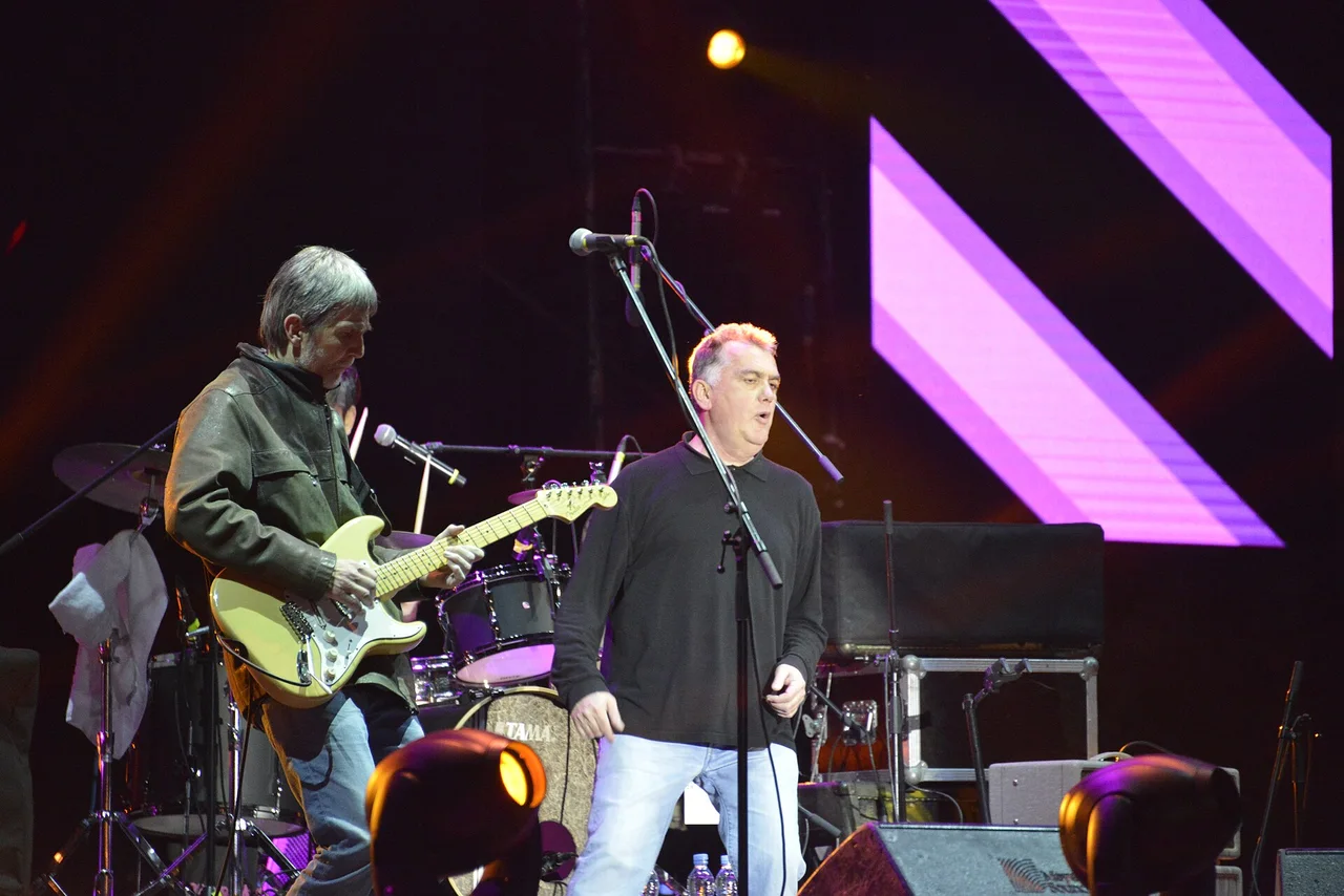 Partibrejkers on a purple-lit stage, the guitarist in a leather jacket playing a cream Stratocaster beside the singer at the microphone