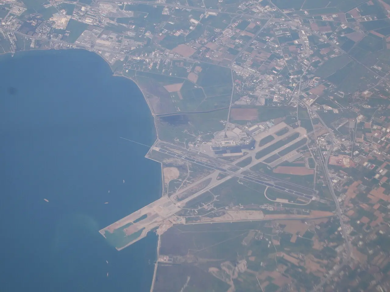 Aerial view of Thessaloniki Makedonia Airport with its runway extending into the Thermaic Gulf