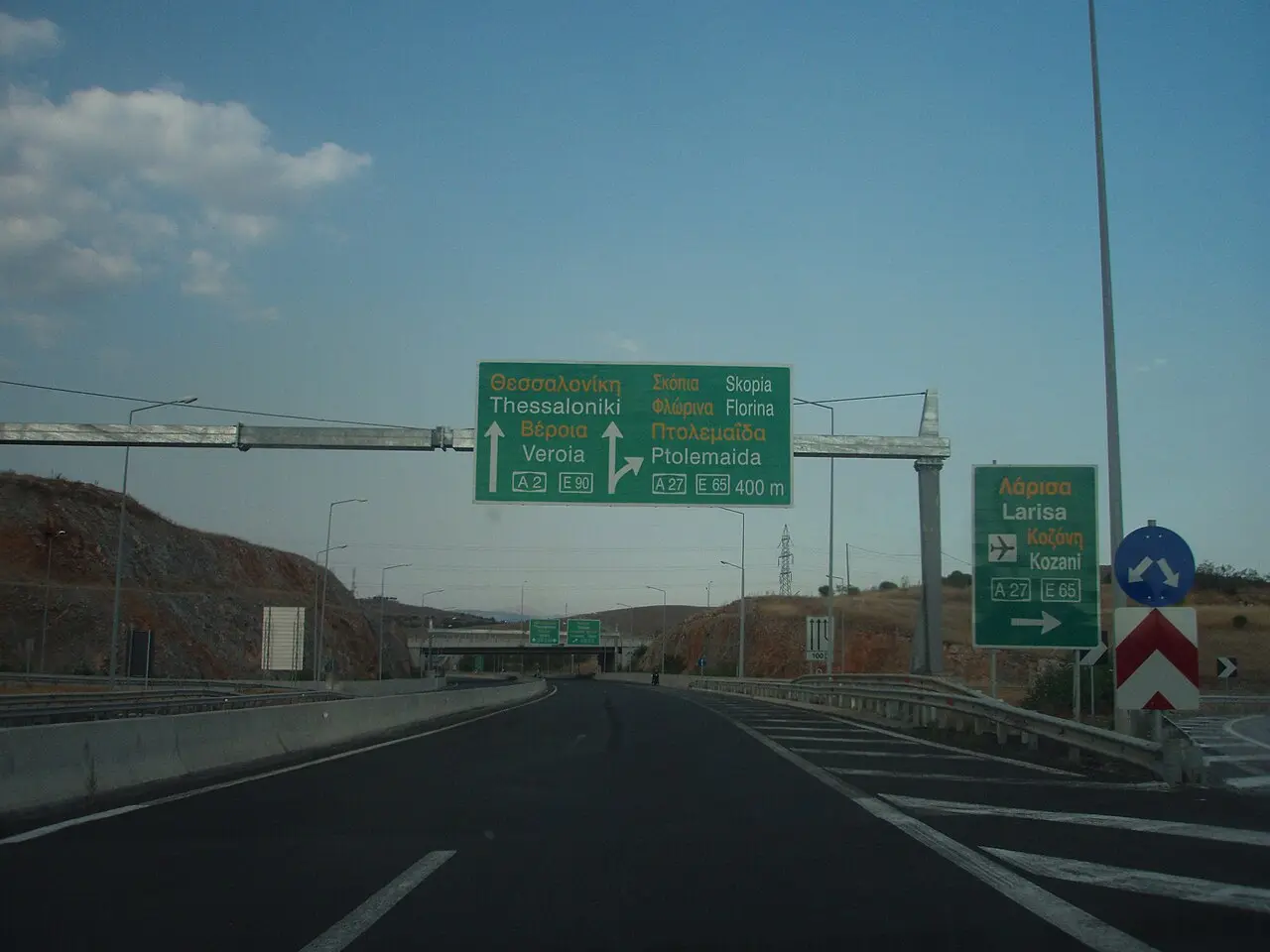 A Greek motorway sign near Kozani pointing straight ahead to Thessaloniki and Veroia, and right toward Florina, Ptolemaida and Skopje on the A27