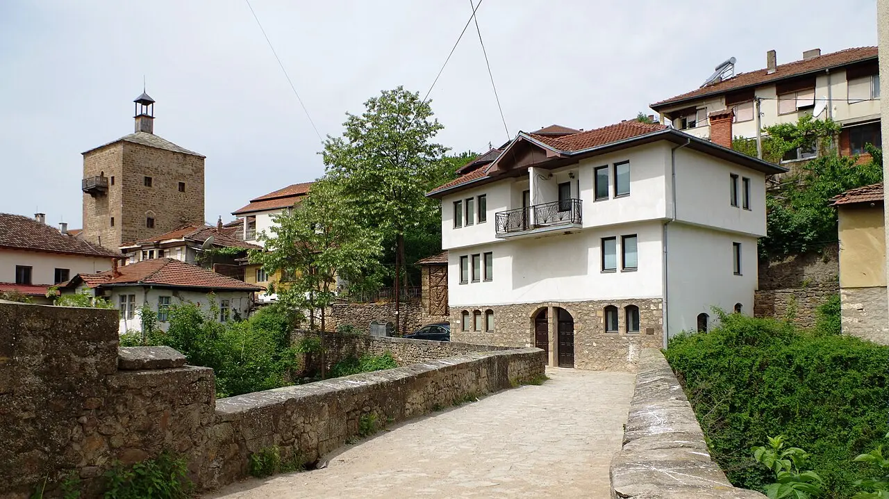 A stone bridge leading to a traditional house in Kratovo, with one of the old defense towers rising behind