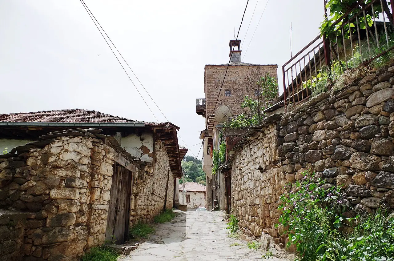 A narrow cobbled lane in Kratovo running between old stone walls with a tower rising at the far end