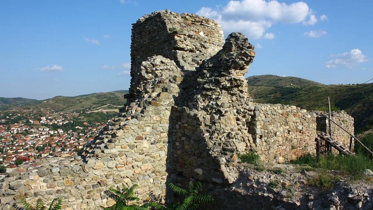 A ruined stone tower of the Isar fortress on the hill above Stip, with the town and hills visible in the distance