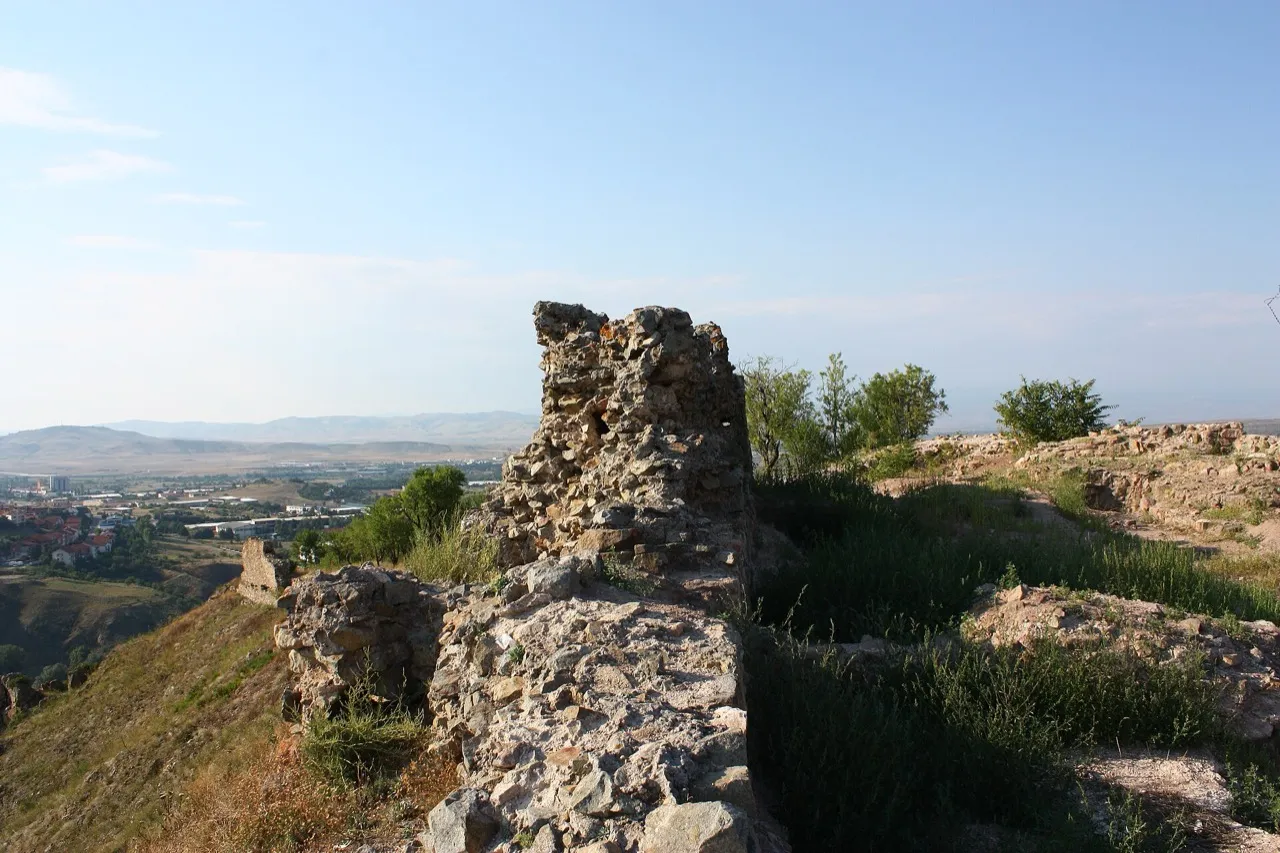 A ruined stone wall and tower on the Isar hill above Stip, with green hills stretching into the distance