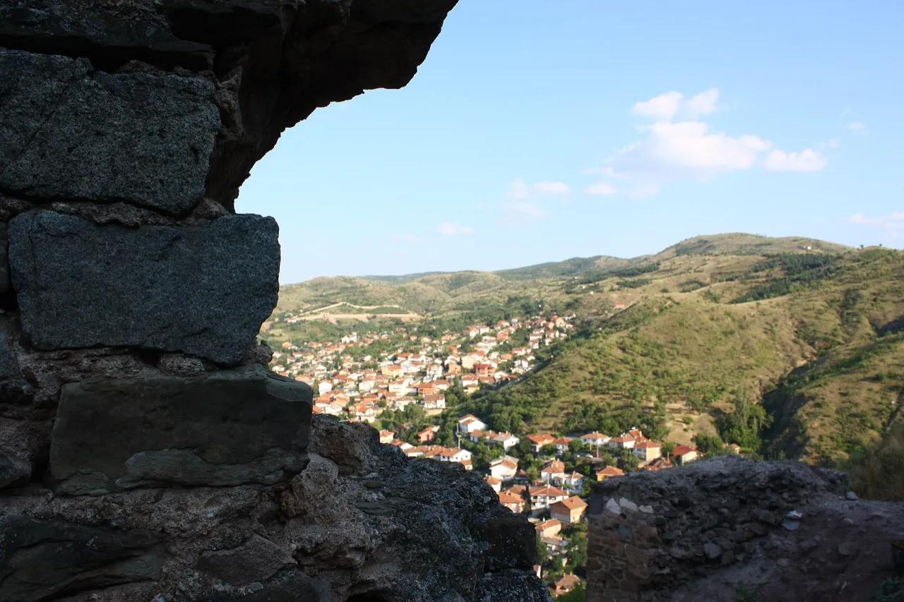 A view through a gap in the Isar fortress walls looking down over a village in the valley below