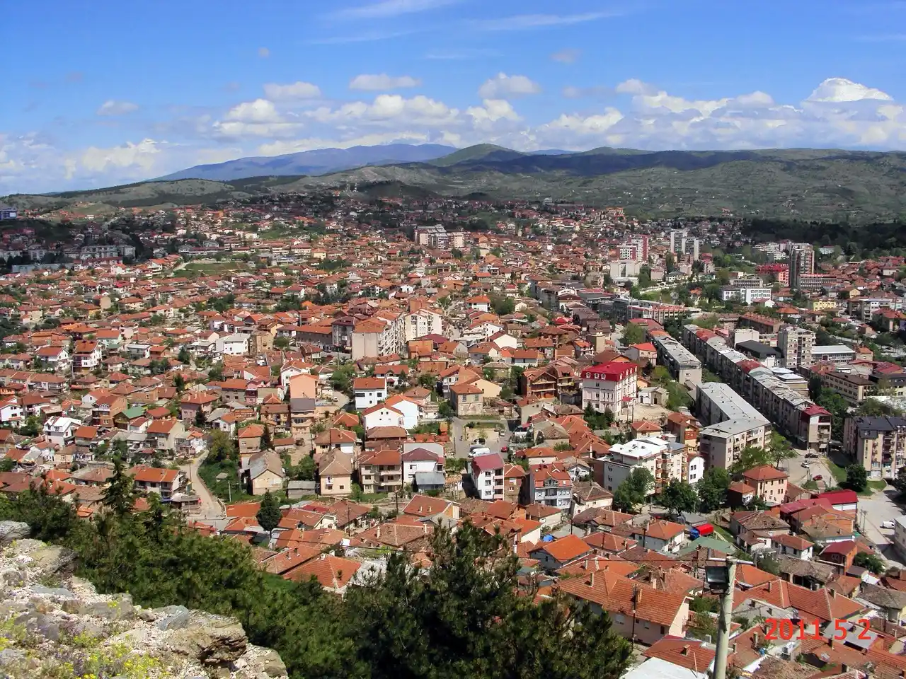 A wide view over the red-tiled roofs of Stip from the Isar hill, with hills and mountains on the horizon