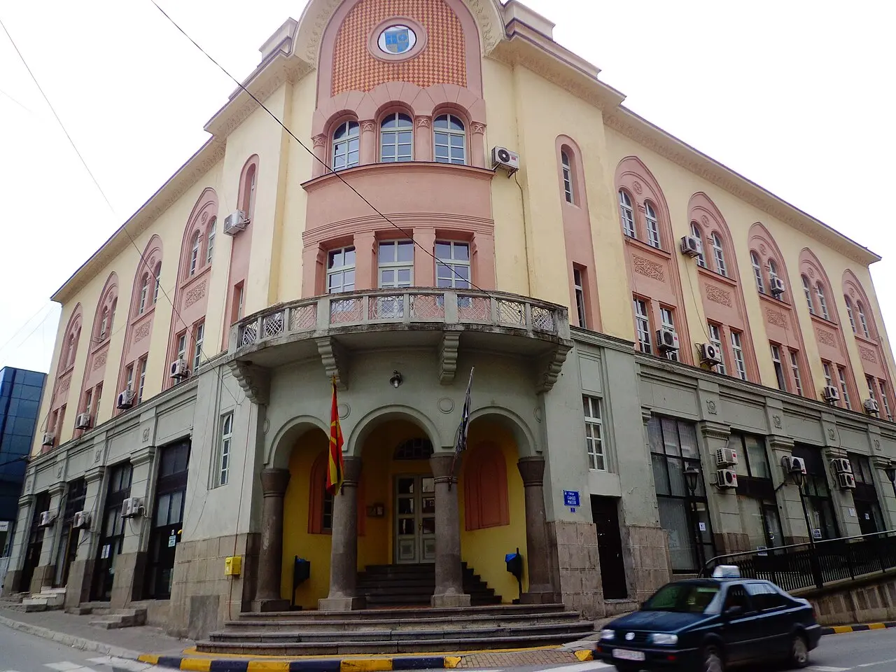 An ornate early 20th century building on a street corner in central Strumica, with the Macedonian flag at the entrance