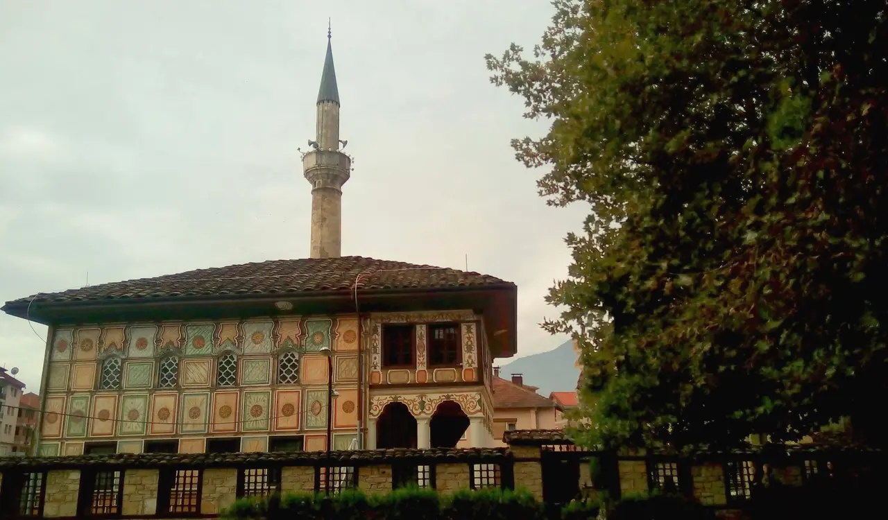 The Painted Mosque of Tetovo, its facade covered in hand-painted geometric and floral panels, with a tall minaret