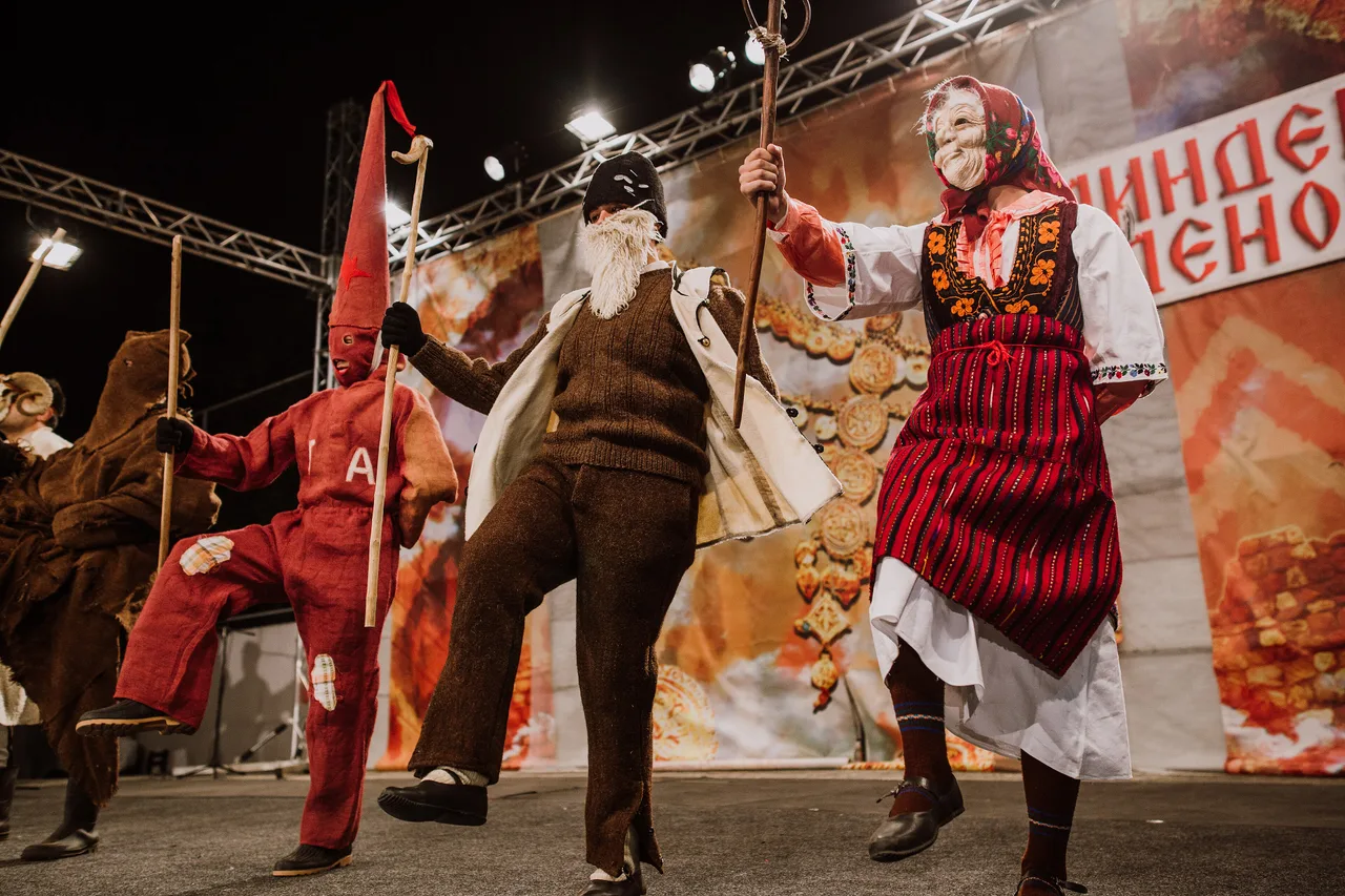 Masked performers in traditional costume dancing on a stage during the Vevčani carnival
