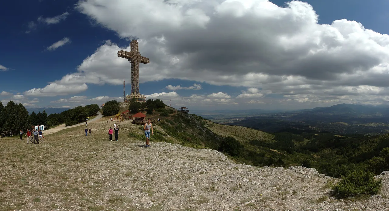 The Millennium Cross on the open summit ridge of Vodno with visitors walking and the plain stretching beyond