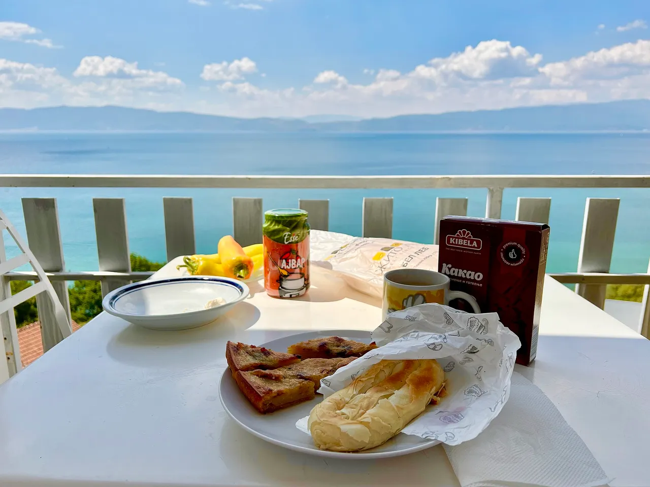 Burek and a can of ajvar on a table overlooking Lake Ohrid