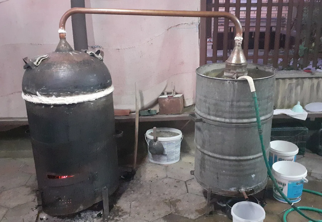 A homemade rakija still with copper piping and a wood fire in an Ohrid backyard