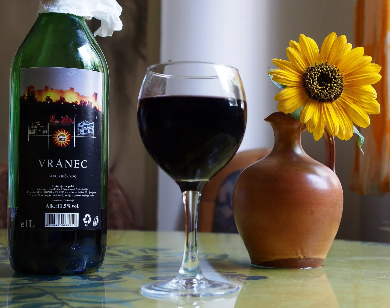 A bottle of Vranec red wine beside a full glass of dark red wine