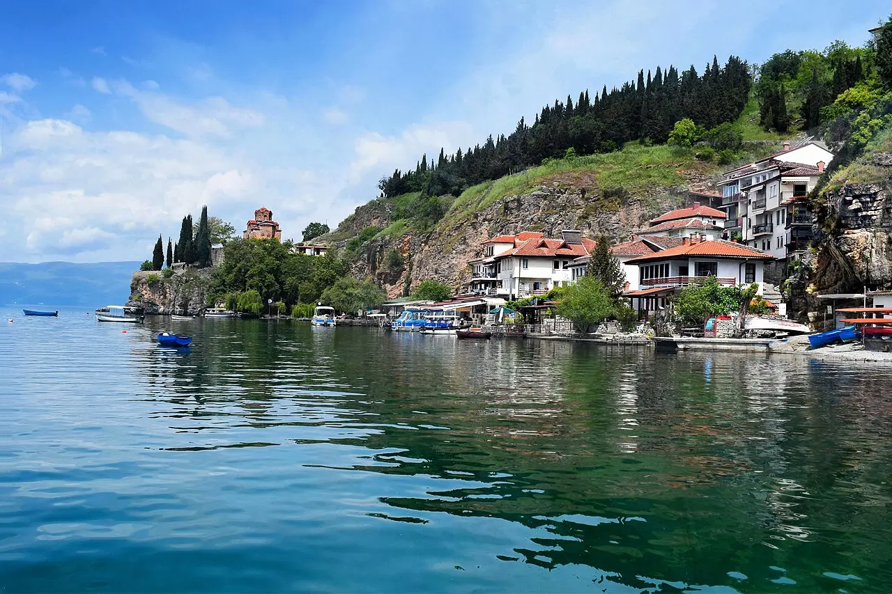 The Kaneo cove on Lake Ohrid, with lakeside restaurant terraces and boats below the Church of St John and its cliff