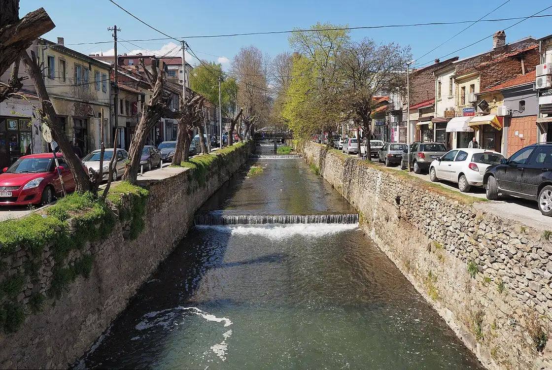 The Dragor river running between stone embankments through the centre of Bitola, with buildings and trees lining both banks