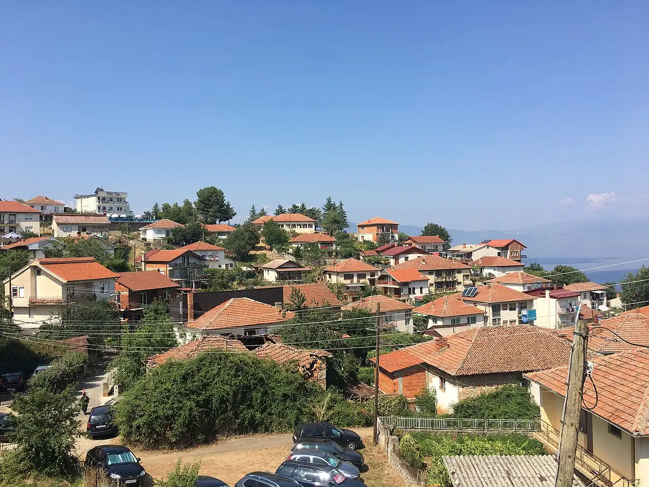 Red-roofed village houses on a green hillside above Lake Ohrid on the quiet southern shore