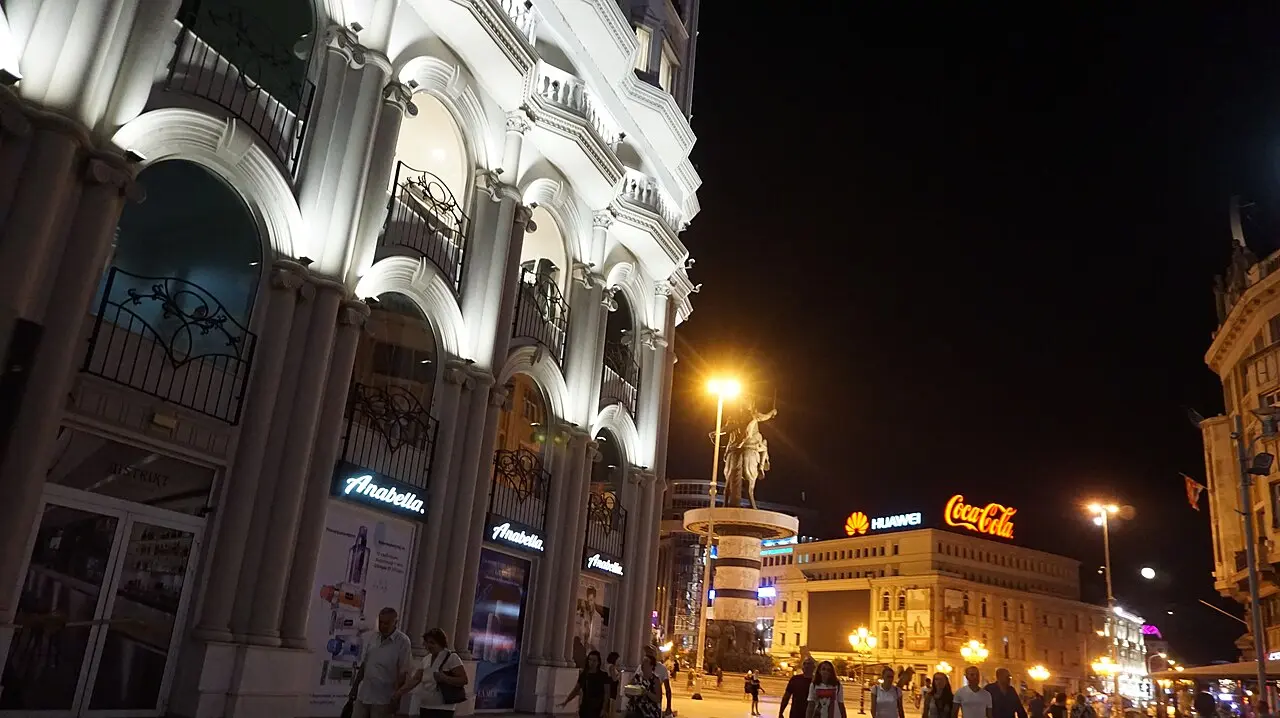 Macedonia Square in Skopje lit up at night, with the Warrior on a Horse fountain and people walking across the square