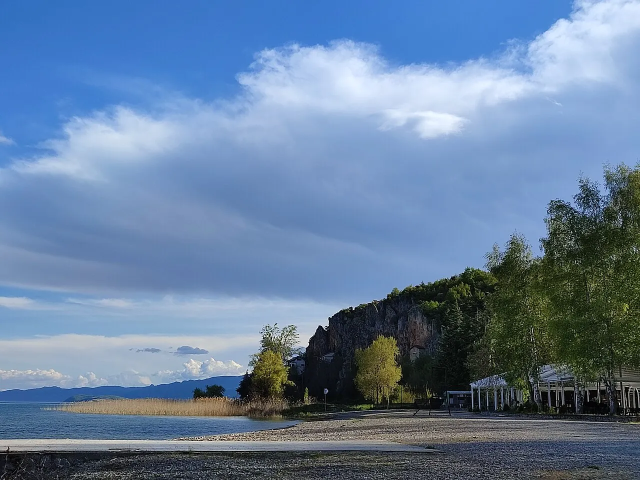 Reed beds, a shingle beach and a lakeside terrace below the wooded cliff at Kalishta near Struga